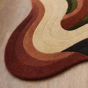 Pode incluir: Um tapete abstrato com um design ondulado e org&acirc;nico. O tapete apresenta uma paleta de cores que vai do vermelho profundo ao laranja, passando pelo bege, verde-oliva e preto, criando um efeito texturizado e sobreposto. Est&aacute; colocado sobre um ch&atilde;o de madeira clara.