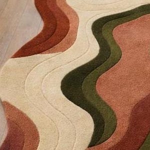 Pode incluir: Um close-up de um tapete com um design ondulado e em camadas. O tapete apresenta tons de bege, castanho e verde, criando um padr&atilde;o abstrato texturizado. O design do tapete assemelha-se a um mapa topogr&aacute;fico ou a uma paisagem estilizada.