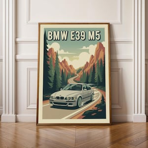 May include: A framed art print featuring a silver BMW E39 M5 car driving on a winding road through a mountain landscape. The print has a vintage style with the text "BMW E39 M5" at the top.