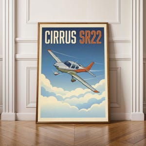 May include: A framed poster depicting a Cirrus SR22 aircraft in flight. The illustration shows the plane with a white and orange colour scheme, flying through a blue sky with fluffy white clouds. The text "CIRRUS SR22" is displayed at the top.