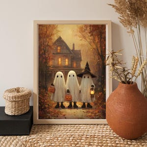May include: A framed Halloween-themed print featuring three cartoon ghosts in white sheets, each holding a jack-o'-lantern or lantern. They stand on a path leading to a spooky house with lit windows, surrounded by autumn trees.