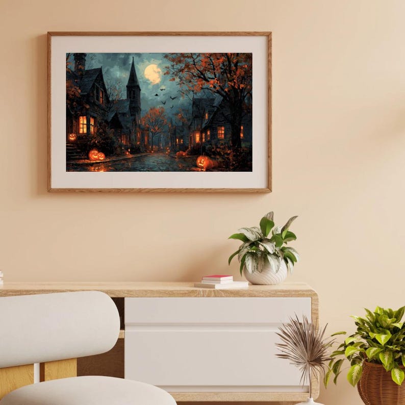 May include: A framed Halloween-themed painting depicts a spooky village scene under a full moon. The artwork features illuminated houses, jack-o'-lanterns, and autumn trees in shades of orange, brown, and black, creating a festive atmosphere.