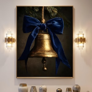 Könnte beinhalten: Ein gerahmter Wandkunstdruck mit einer großen, verwitterten, goldfarbenen Glocke, die an einer rustikalen Schnur hängt. Eine auffällige, tiefblaue Samtschleife ist oben an der Glocke befestigt, vor einem dunklen Hintergrund mit Tannennadeln.