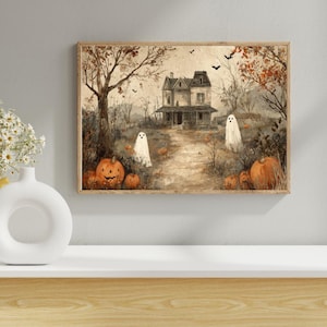 Op de afbeelding: Een ingelijste Halloween-print met een spookhuis, pompoenen en geesten. Het kunstwerk heeft een vintage esthetiek met gedempte kleuren, waaronder oranje, bruin en beige. De scène toont een spookhuis op een pad met pompoenen en geesten.