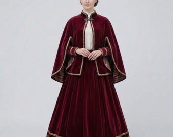 May include: A deep burgundy velvet cape and matching long skirt ensemble. The cape features a high collar with a metal clasp, gold trim along the edges, and a plaid lining. The skirt is floor-length with two horizontal gold bands at the hem.