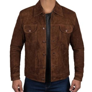 Può includere: Giacca in pelle scamosciata marrone con chiusura a bottoni, due tasche sul petto e colletto. La giacca ha un design classico e un aspetto leggermente usurato.