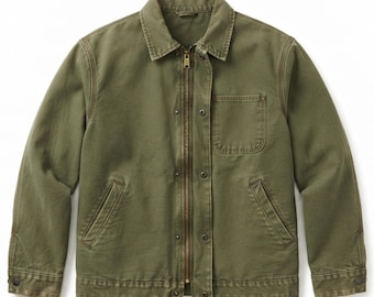May include: An olive green canvas jacket featuring a pointed collar, a full-length brass-toned metal zip, and a snap-button storm flap. The jacket includes one chest pocket, two slanted side pockets, and long sleeves with buttoned cuffs.