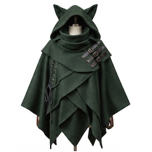 May include: A dark forest green hooded cape featuring pointed cat-like ears on the hood. The garment includes three brown leather-look straps with metal buckles on the right shoulder and a vertical lace-up detail with dark cord on the left side.