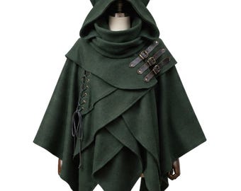 May include: A dark forest green hooded cape featuring pointed cat-like ears on the hood. The garment includes three brown leather-look straps with metal buckles on the right shoulder and a vertical lace-up detail with dark cord on the left side.