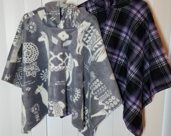 May include: Two fleece ponchos, one gray with a white geometric pattern and the other black with a purple and white plaid pattern.