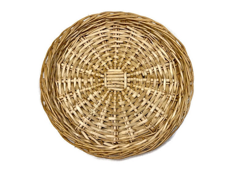 May include: A round woven wicker charger plate with a natural brown color.