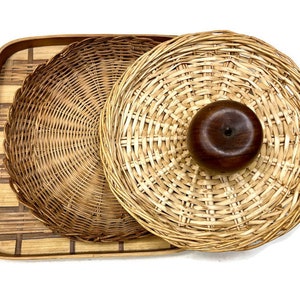 May include: A set of three woven wicker baskets, one large and two smaller, with a wooden knob on the top of the largest basket.