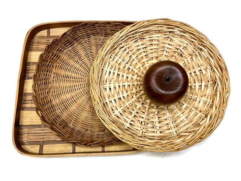 May include: A set of three woven wicker baskets, one large and two smaller, with a wooden knob on the top of the largest basket.