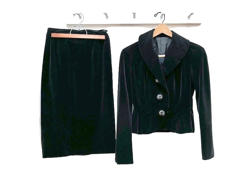 May include: A black velvet skirt and jacket set. The jacket has a wide collar and button closure.