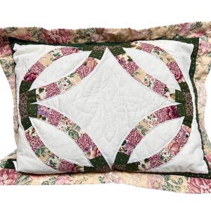 Peut inclure: Un oreiller rectangulaire avec un centre blanc et un motif floral. L'oreiller présente un motif matelassé avec des accents vert foncé et floraux. La bordure est un motif floral avec des tons roses et crème.
