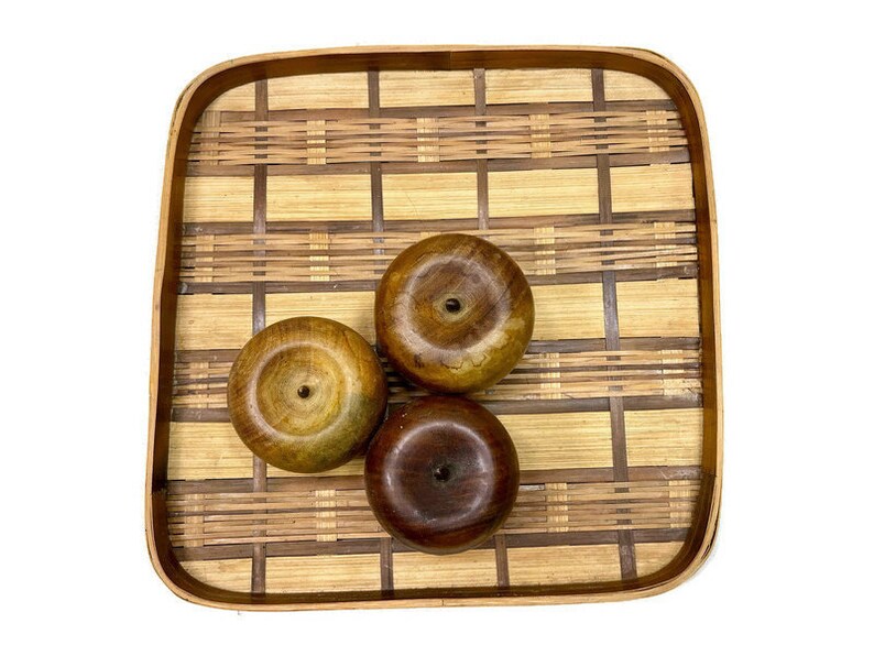 May include: Three wooden bowls with a natural wood finish are arranged on a woven bamboo tray. The tray has a light brown color and a square shape.