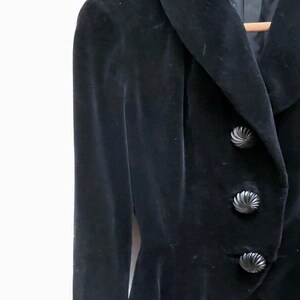 May include: A black velvet jacket with a wide collar and three large, decorative buttons.
