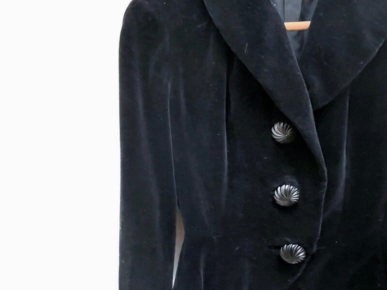 May include: A black velvet jacket with a wide collar and three large, decorative buttons.