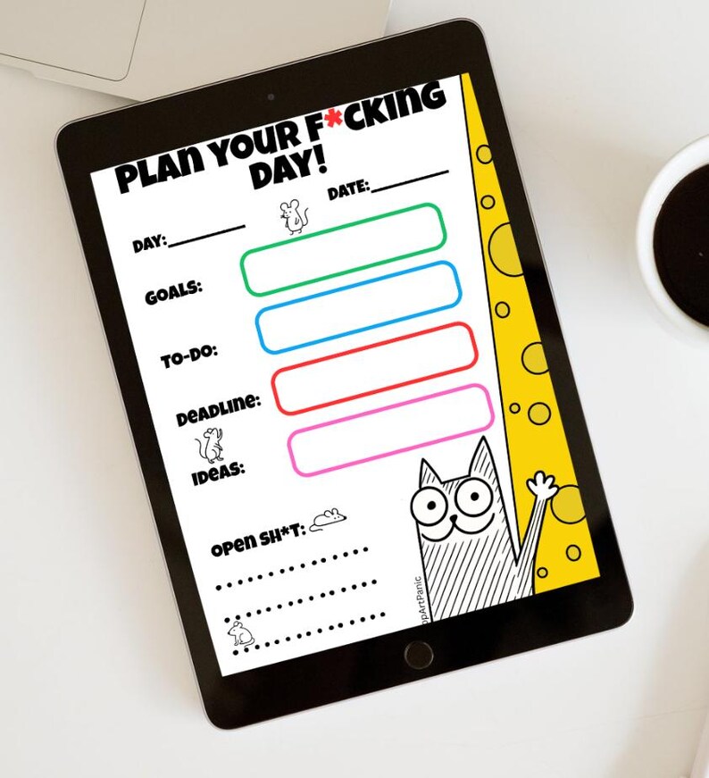 May include: A black tablet displaying a daily planner with the text "PLAN YOUR F*CKING DAY!". The planner includes sections for day, goals, to-do, deadline, and ideas, with a cartoon cat illustration. A cup of coffee is visible.