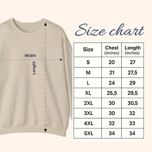 May include: A beige crewneck sweatshirt shown with a size chart. The chart displays measurements in inches for sizes S through 5XL, detailing chest and length dimensions. Arrows indicate the width and length measurement points on the garment.