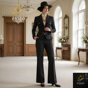 May include: A charcoal grey suit featuring a fitted jacket with gold buttons and flared trousers. The person is wearing a cream blouse and a dark hat. The suit is from Zavio Suits. The suit's design is reminiscent of the 1970s.
