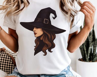 May include: White t-shirt featuring a graphic of a woman wearing a black witch hat with a buckle. The woman has long brown hair and red lipstick. The design is centered on the shirt.