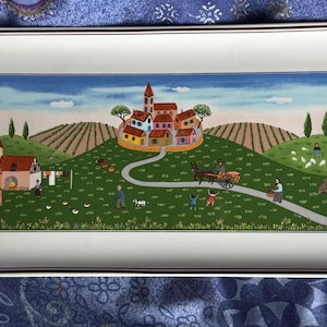 以下が含まれることがあります： 絵画の村のシーンが描かれた長方形のサービングトレイ。アートワークは、曲がりくねった道、人物、馬車のある、丘の上のカラフルな村を描いています。トレイは白い表面と銀色のトリムが付いています。