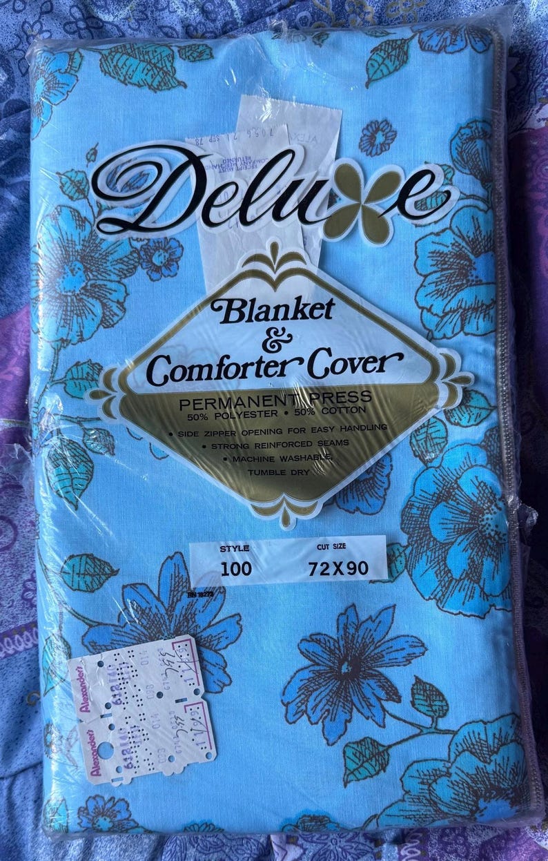 K&ouml;nnte beinhalten: Hellblaue Deluxe Decke und Bettdeckenbezug mit blau-braunem Blumenmuster. Die Verpackung tr&auml;gt die Aufschrift "Blanket & Comforter Cover". Die Ma&szlig;e sind 183 x 229 cm.