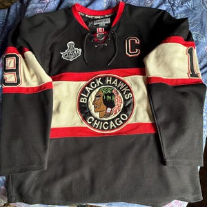 May include: Black Chicago Blackhawks hockey jersey with white and red accents. Features the team logo, the number 9 on the left sleeve, and the number 1 on the right sleeve. Includes the word "Final" on the chest.
