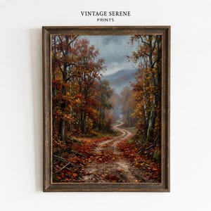 Può includere: Una stampa artistica incorniciata intitolata VINTAGE SERENE PRINTS che presenta un dipinto a olio di un sentiero sterrato tortuoso attraverso un bosco autunnale. La scena mostra alberi con fogliame arancione, rosso e marrone, foglie cadute a terra e montagne in lontananza sotto un cielo nuvoloso.