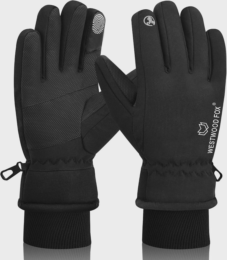 May include: Black gloves with a textured palm and fingertip design. The gloves have a ribbed cuff and a zipper detail. The brand name "WESTWOOD FOX" is printed in white on the side. The gloves are designed for touchscreen use.