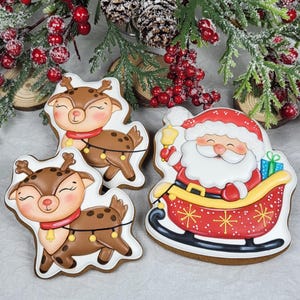 May include: Gingerbread cookies in the shape of reindeer and Santa Claus in a sleigh. The reindeer cookies are brown with red scarves and yellow bells. The Santa cookie is in a red sleigh with a yellow trim and holding a bell.
