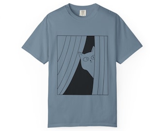 May include: Pale blue t-shirt with a black and white cartoon cat design. The cat is peeking through curtains. The design is enclosed in a black square. The t-shirt has a crew neck and short sleeves.