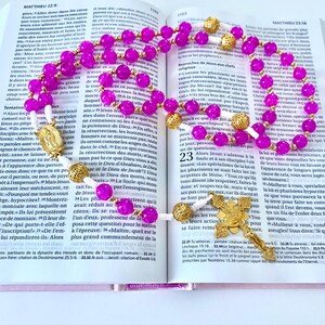 Traditional hand-knotted Christian Catholic rosary beads in fuchsia pink with a medal of the Blessed Virgin Mary for praying the rosary