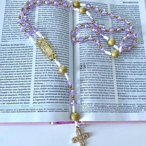 Traditional hand-knotted Christian Catholic rosary beads with purple lilac beads and a medal of the Blessed Virgin Mary for praying the rosary