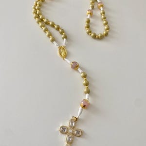 Traditional Christian Catholic rosary, hand-knotted, made of gold beads and rose quartz beads. Rosary to pray to the Virgin Mary