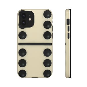 May include: A phone case with a domino design. The case is off-white with black dots arranged in a domino pattern. The side view shows a black border and buttons.