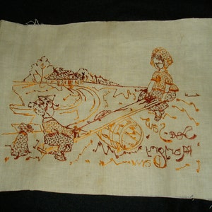 May include: A rectangular piece of off-white fabric featuring a brown embroidered scene of two children playing on a seesaw with a dog nearby. The embroidery includes a landscape with a house and trees in the background, along with the text See-Saw.