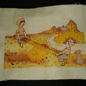 May include: A rectangular piece of off-white fabric featuring an embroidered scene of two children on a seesaw with a dog, a house, and trees in the background. The text "See-Saw Marjory Daw..." is embroidered in brown thread on the left side.