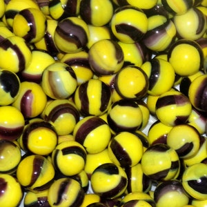 May include: A collection of yellow and black marbles with swirling patterns. The marbles are arranged in a close-up view, showcasing their intricate designs.