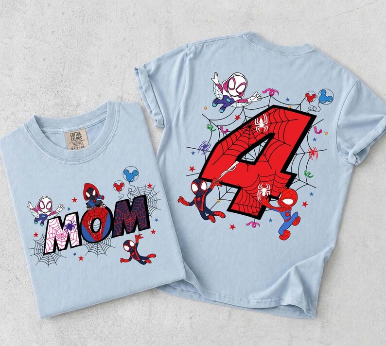 May include: Two light blue t-shirts with Spider-Man graphics. One shirt features the word "MOM" with a spider web design, and the other has a large red number "4" with a spider web design. Both shirts have Spider-Man characters.