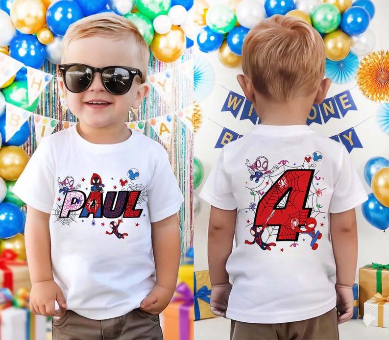 May include: A white t-shirt featuring the name "PAUL" in a colorful, web-themed design with Spider-Man characters. The back of the shirt displays a large red number "4" with a spiderweb design and more Spider-Man graphics. The shirt is for a child.
