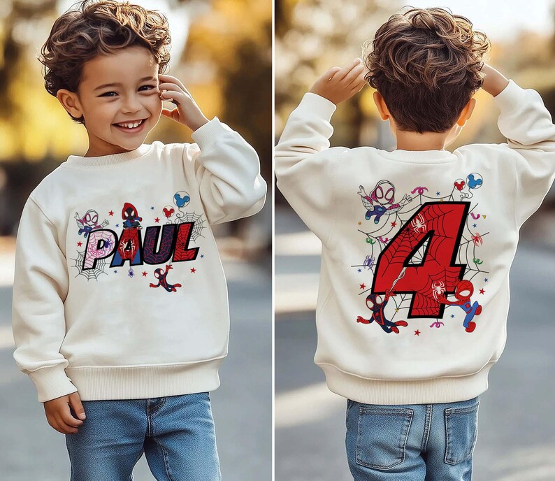 May include: Cream-colored sweatshirt featuring the name "PAUL" in a colorful, web-themed design with Spider-Man graphics. The back of the sweatshirt displays a large red number "4" with Spider-Man and web details, suitable for a child's birthday.