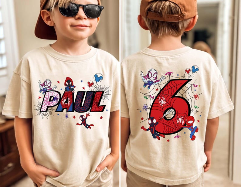 May include: Beige t-shirt featuring a colorful Spider-Man design. The front displays the name "PAUL" in a webbed font, with Spider-Man characters and stars. The back shows a large red number "6" with Spider-Man graphics, ideal for a birthday.