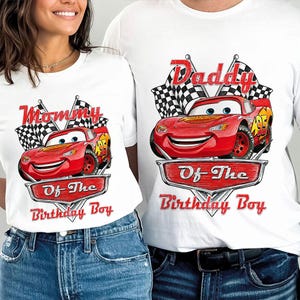 Puede incluir: Camisetas blancas con un dise&ntilde;o de coche de carreras de dibujos animados rojo. Una camiseta dice "Mommy Of The Birthday Boy" y la otra "Daddy Of The Birthday Boy". Ambas tienen banderas a cuadros.