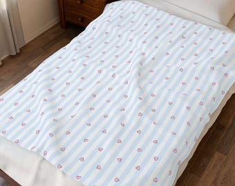 Coperta in velluto a righe azzurre pastello, con stampa a cuoricini rosa.