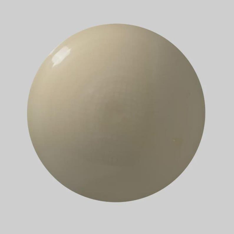 May include: A smooth, spherical object with a creamy, off-white color. The surface has a glossy sheen, reflecting light. The shape is perfectly round, and the overall appearance is simple and elegant. The object appears to be made of a solid material.