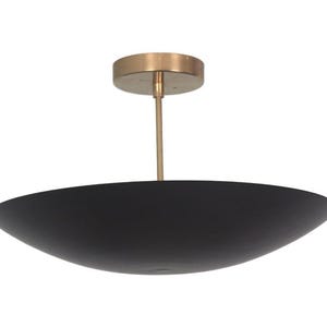 May include: A modern ceiling light fixture with a black, bowl-shaped shade. The fixture has a brass-colored canopy and a slender rod. The shade is approximately 20 inches in diameter, and the overall design is minimalist and elegant.