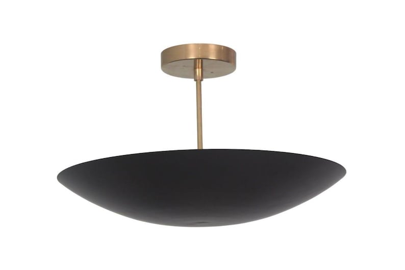 May include: A modern ceiling light fixture with a black, bowl-shaped shade. The fixture has a brass-colored canopy and a slender rod. The shade is approximately 20 inches in diameter, and the overall design is minimalist and elegant.