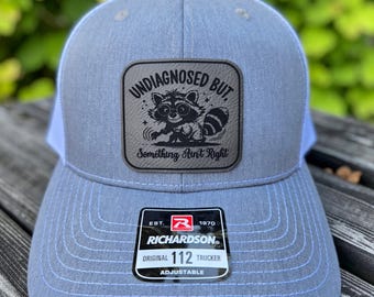 Raccoon Leather Patch Trucker Hat: "Undiagnosed But Something Ain't Right"